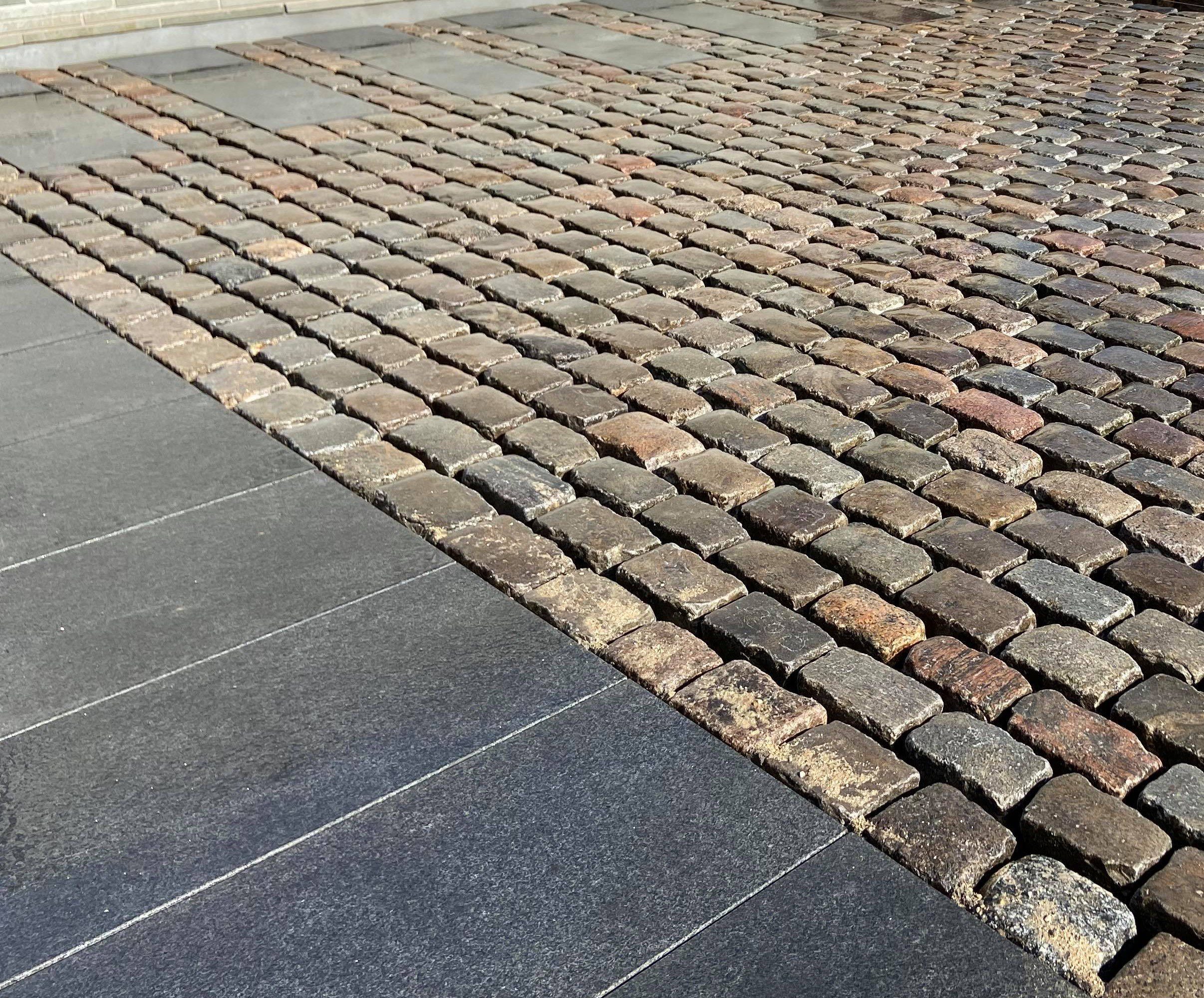 Slidt nordisk brostens belægning med basalt granit indkørsel. Genanvendelse af slidt granit